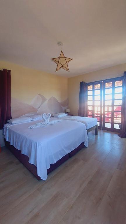 a bedroom with two beds and a large window at Espaço conforto e tranquilidade CASAVEG in Canoa Quebrada
