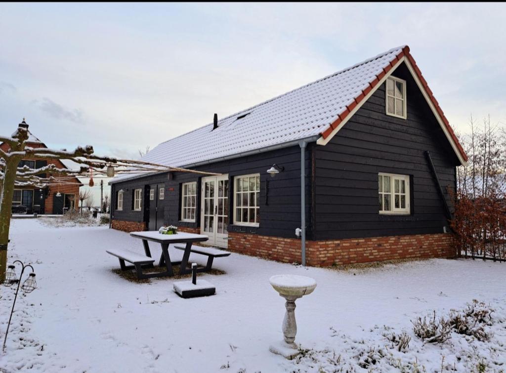 BergambachtB&B De Oase的雪中带桌子的黑色房子