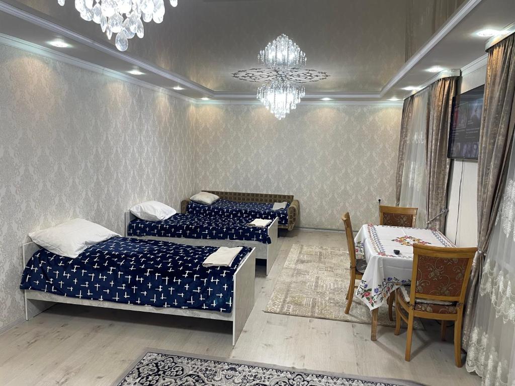 een kamer met 3 bedden en een kroonluchter bij Nur Hotel in Karakol