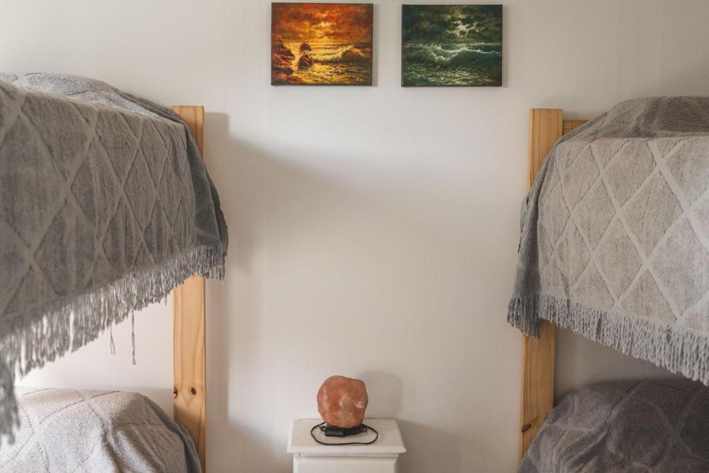 een slaapkamer met twee eenpersoonsbedden en twee schilderijen aan de muur bij Casa de Buda Chapadmalal in Chapadmalal