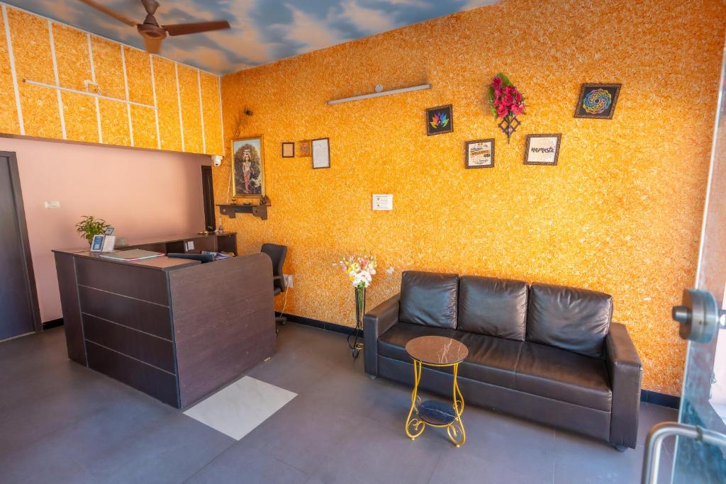 a waiting room with a couch and a yellow wall at Aryas Residency- Near Isha Foundation Coimbatore & Adiyogi statue in Alāndurai
