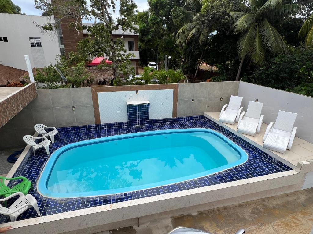 een zwembad met witte stoelen en een zwembad bij Flats Brisa Antunes in Maragogi