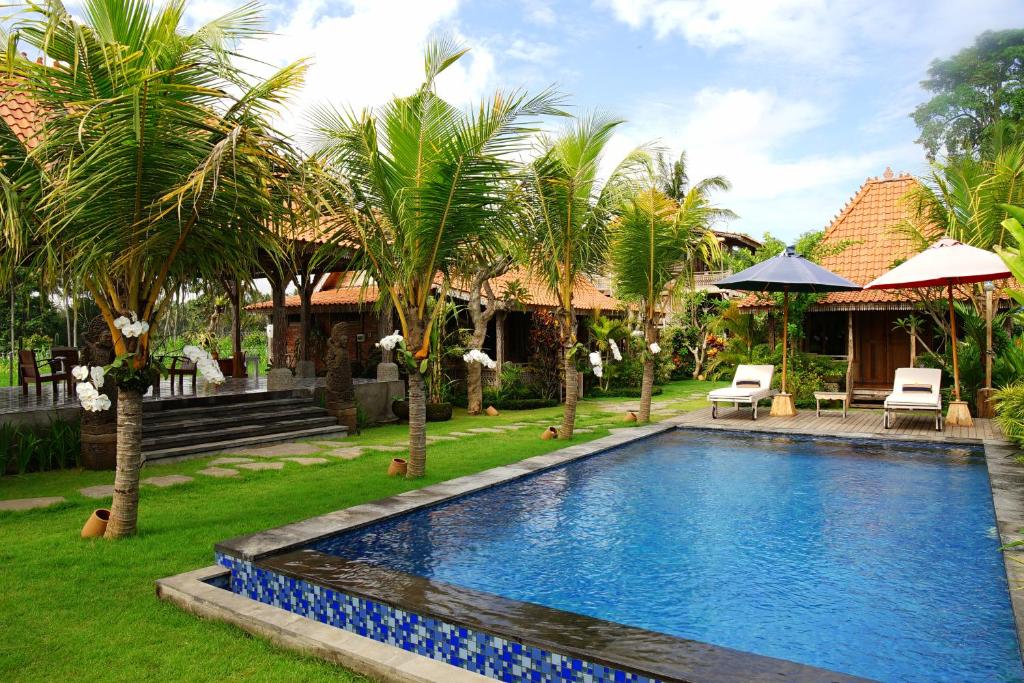 ein Swimmingpool in einem Garten mit Palmen in der Unterkunft Nauna Villa Bali in Ubud