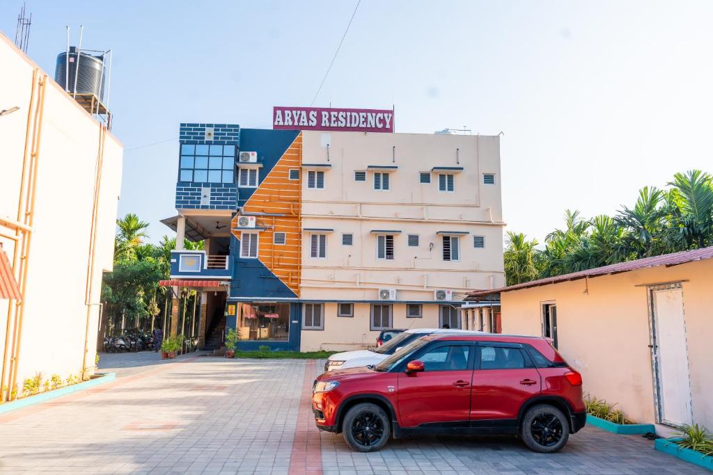 een rode auto geparkeerd voor een gebouw bij Aryas Residency- Near Isha Foundation Coimbatore & Karunya University in Alāndurai