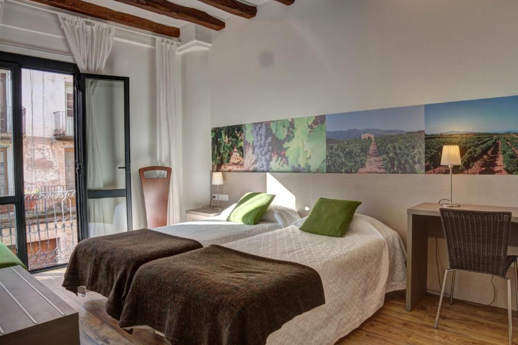 a bedroom with a bed with green pillows and a desk at Hostal Agrobotiga 7 de Ribera in Móra d'Ebre