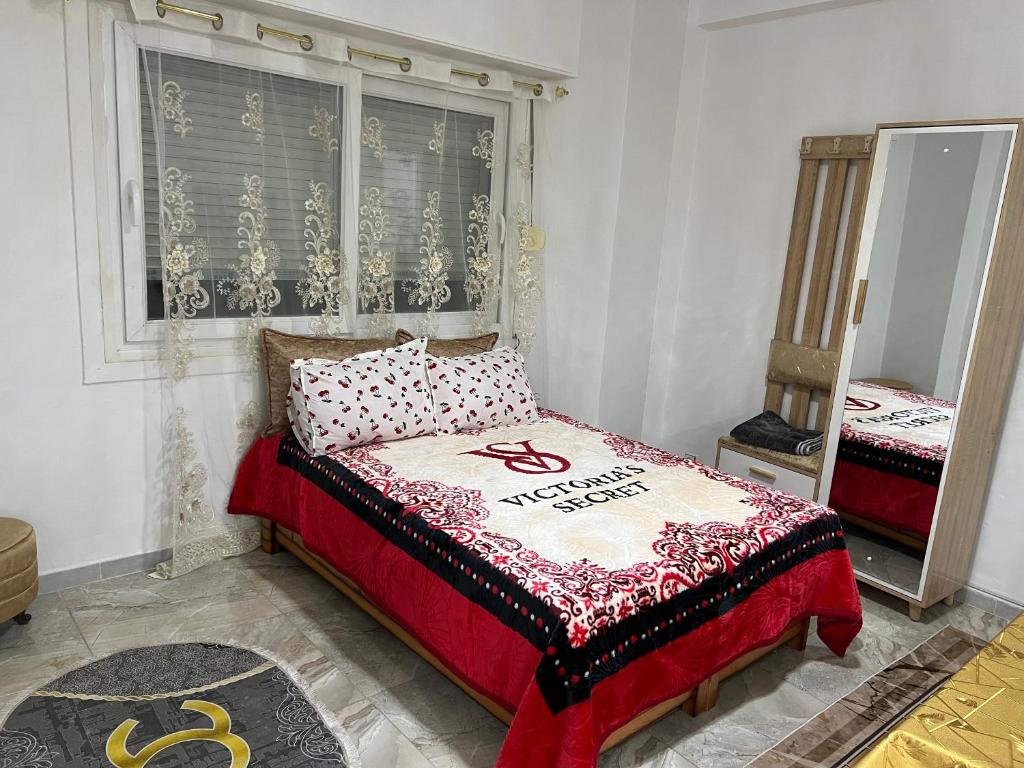 een slaapkamer met een bed, een raam en een spiegel bij Magnifique Studio in Mostaganem