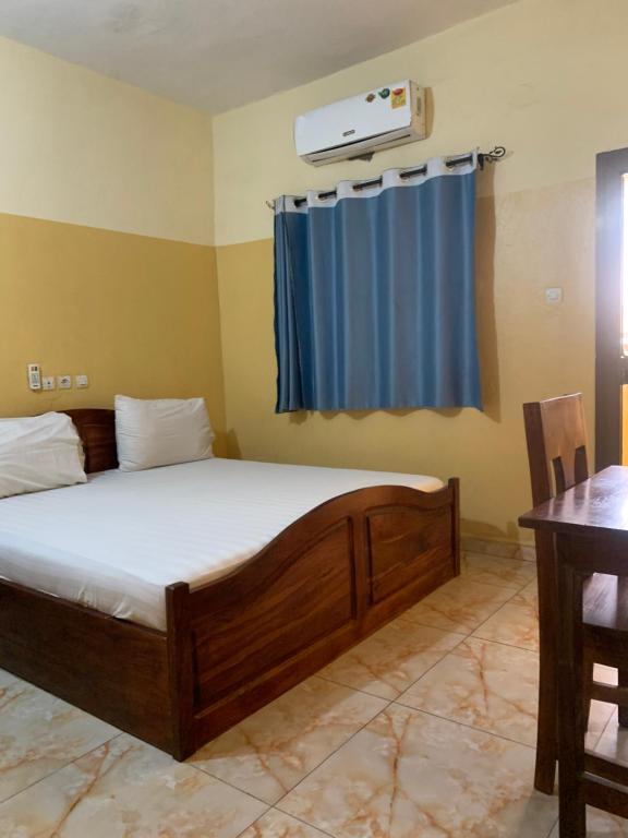 une chambre avec un lit et un rideau bleu dans l'établissement MOTEL GLORY EL dilora, à Lomé