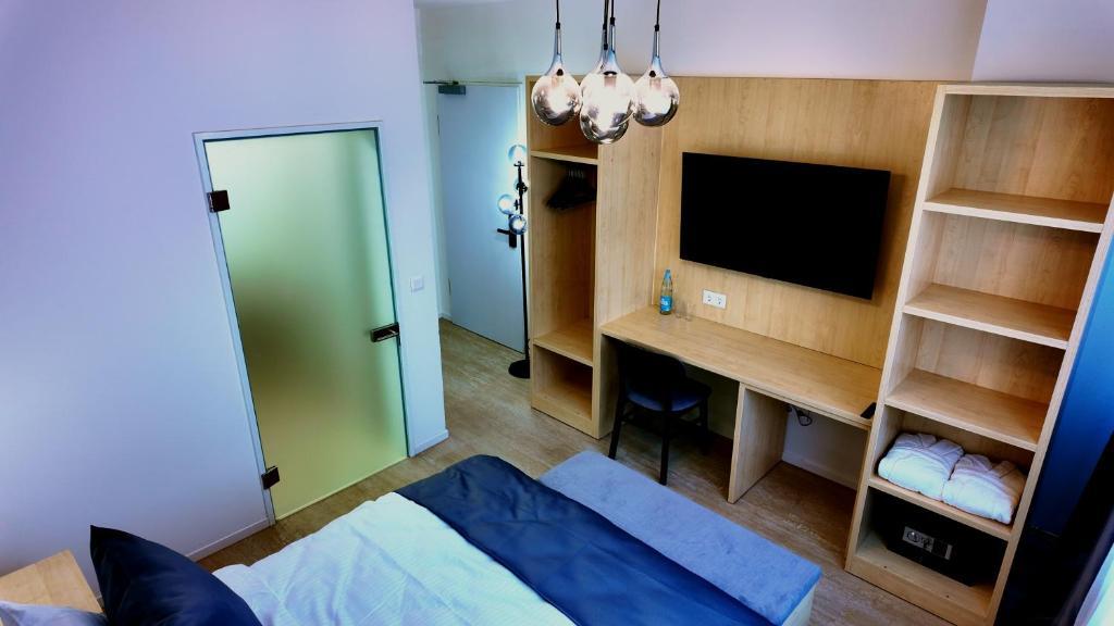 een slaapkamer met een bed en een bureau met een televisie bij Niko Hotel am Hannover Hbf in Hannover