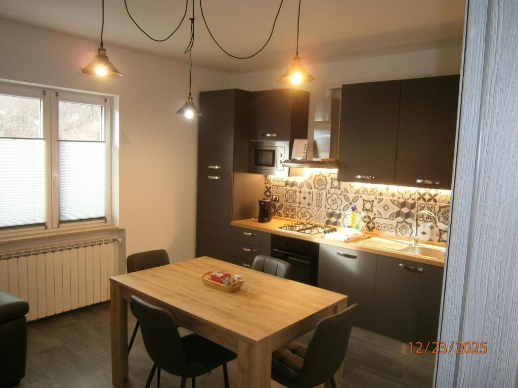 una cucina con un tavolo di legno e un tavolo e sedie di Residence ai fiori - Simone Apartment ad Arta Terme