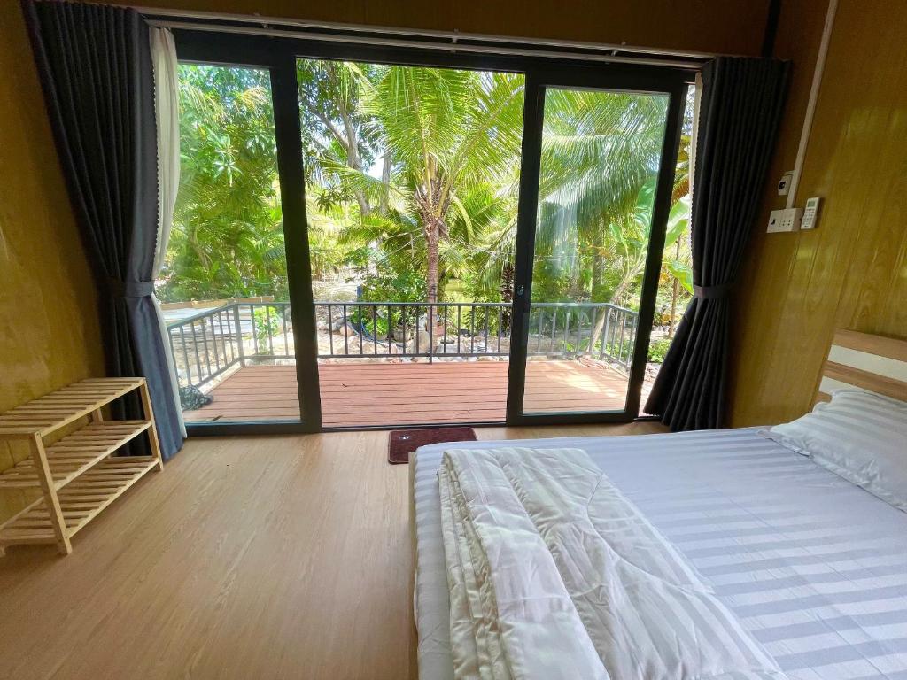 a bedroom with a bed and a sliding glass door at Farm Tân Tiến in Ấp Bình Thạnh
