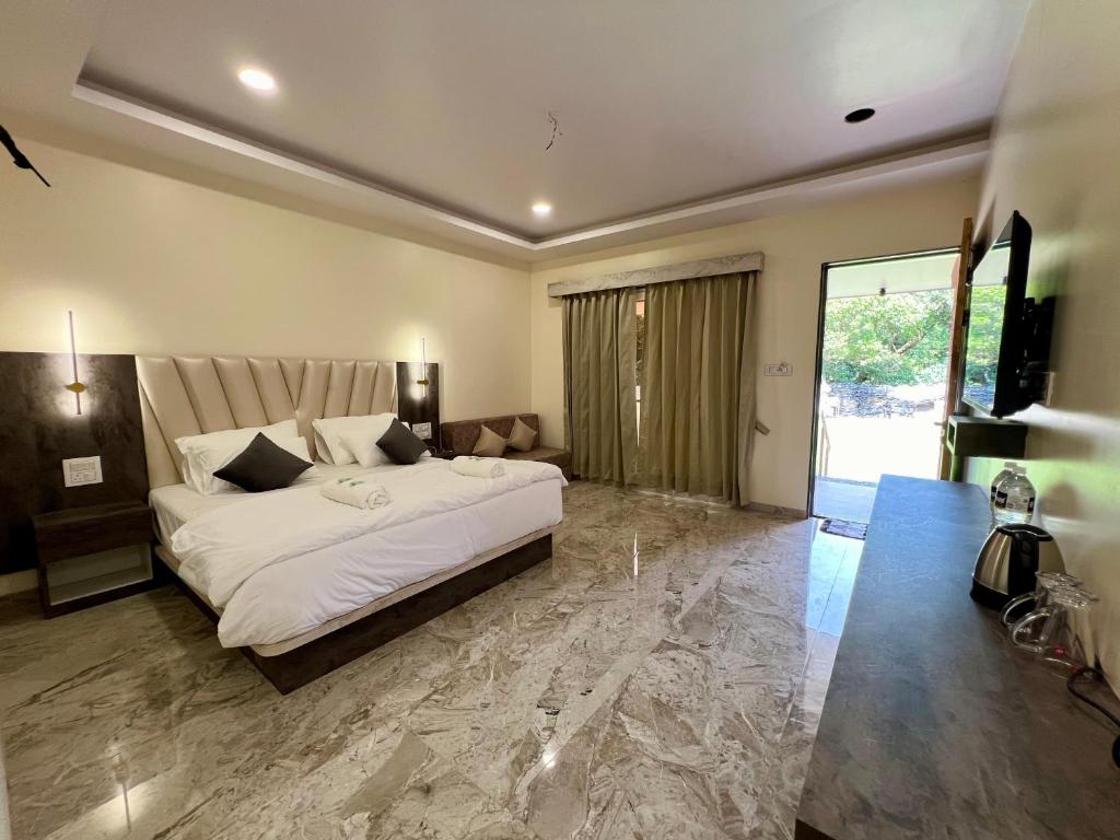 a bedroom with a large bed and a large window at ARANYAM By StarGlaze Retreat in Mahabaleshwar