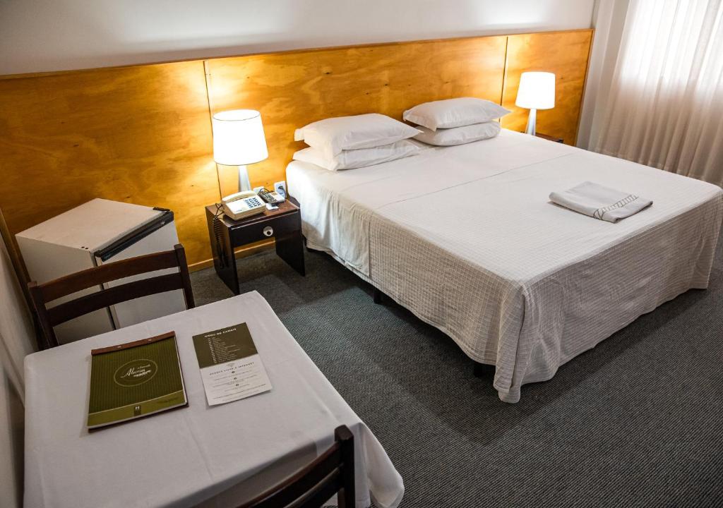 une chambre d'hôtel avec un lit, une table et des chaises dans l'établissement Planalto Hotel, à Canoinhas