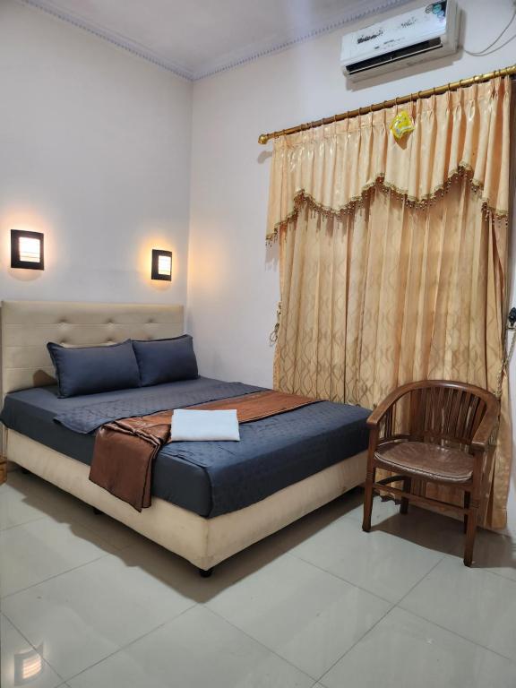 een slaapkamer met een bed, een stoel en een raam bij Among Rogo Syariah in Yogyakarta