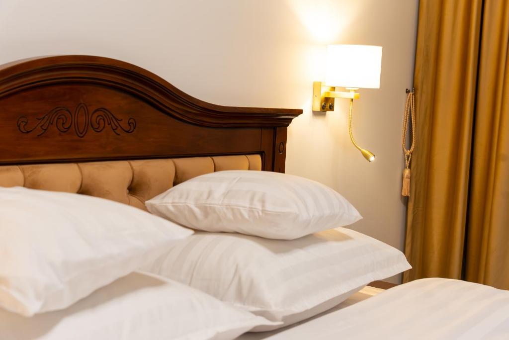 een bed met twee witte kussens en een houten hoofdeinde bij Casa Doseanu in Oradea