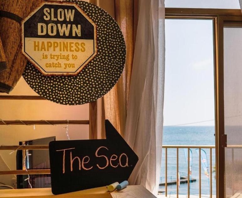 Ein Schild mit der Aufschrift „Entschleunige“ sagt: Das Glück wartet auf dich. in der Unterkunft Oyster 2 Beachfront bliss in Qbajjar