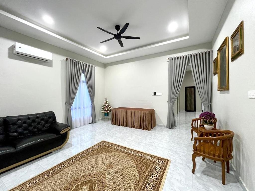 un salon avec un canapé noir et une table dans l'établissement Baba Homestay, à Macang