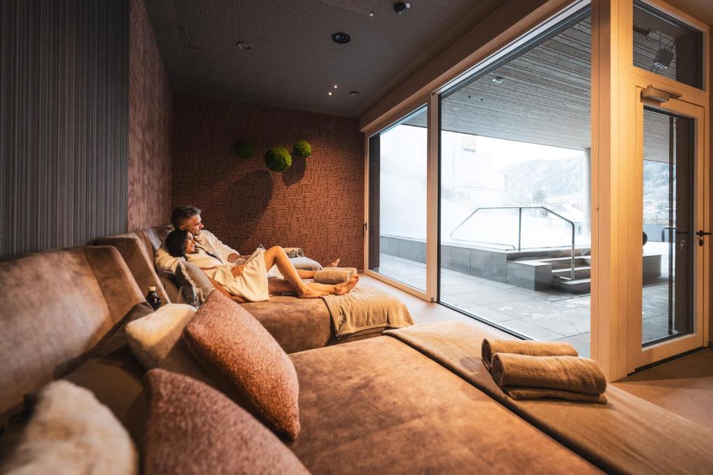 een man op een bank in een woonkamer bij Alpine Boutique Hotel wollée in Schladming