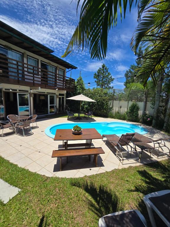 a picnic table and chairs next to a swimming pool at Pousada Casa Campeche - Floripa in Florianópolis
