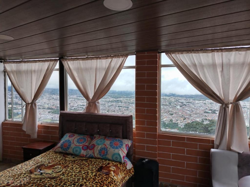 una camera con un letto e due grandi finestre di Hospedaje Mágico Arcángel a Ibarra