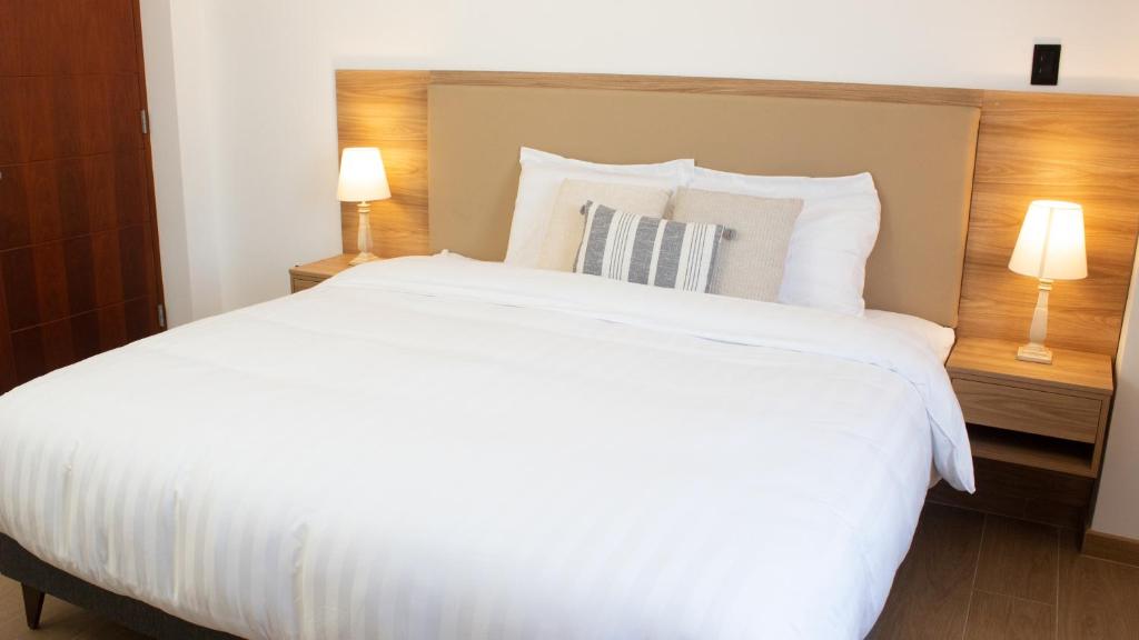 - un grand lit blanc dans une chambre d'hôtel avec deux lampes dans l'établissement Hostal Llampayec, à Chiclayo