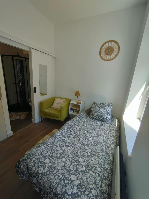 een slaapkamer met een bed en een stoel bij AB Studio in Roubaix
