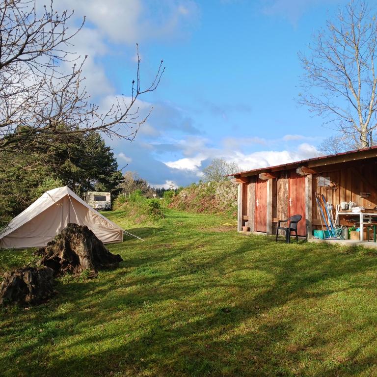 a tent in the grass next to a barn at Camping à la Ferme de la Marette in Gluiras