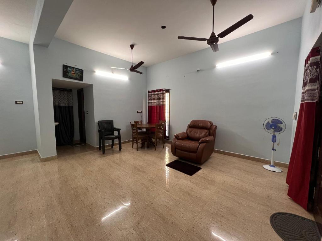 a living room with a leather chair and a table at MUBSS Homestay in Tiruchirappalli