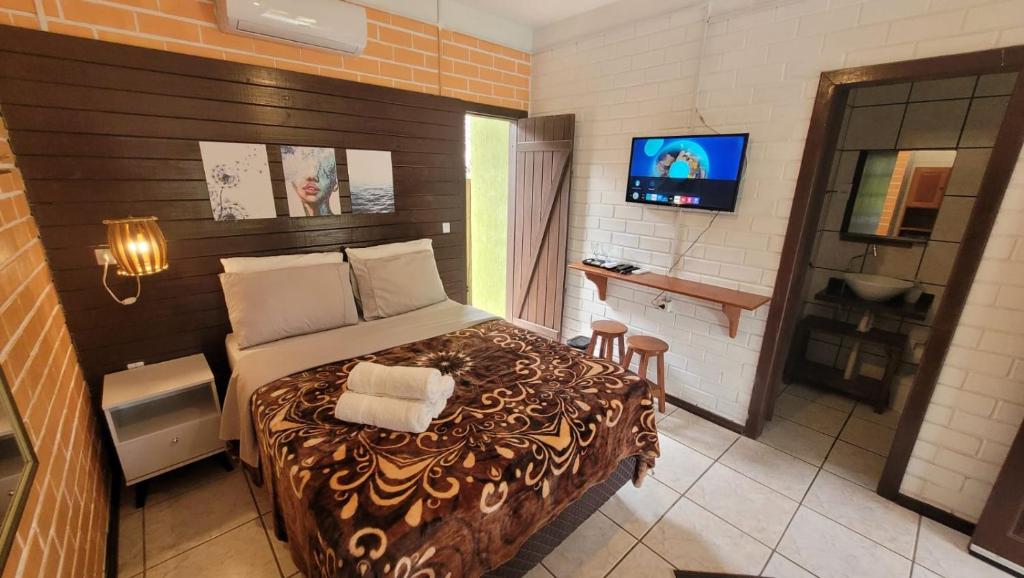 een slaapkamer met een bed en een televisie. bij Pousada Uluwatu, Praia do Rosa in Praia do Rosa