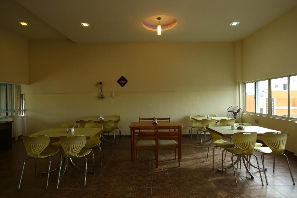a restaurant with tables and chairs in a room at Capital O J Service Appartment in Chennai