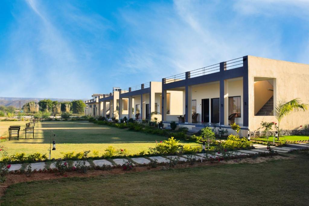 eine Reihe von Häusern mit Rasen davor in der Unterkunft Ranthambore Village Serai in Khilchīpur