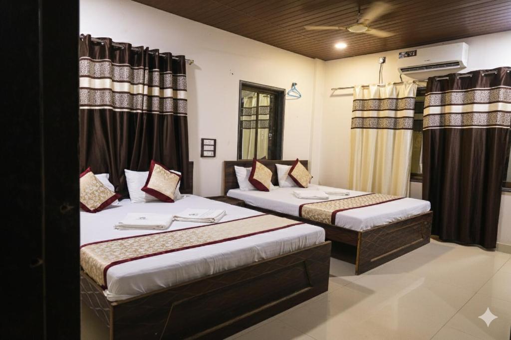 twee bedden in een kamer met gordijnen bij Konkan Paradise-Siddhivinayak,Devbag Beach Resort in Malvan