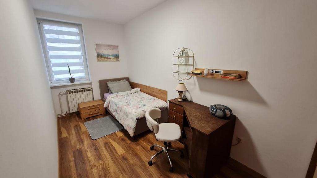 a bedroom with a bed and a desk and a chair at Sabina apartmani in Tuzla