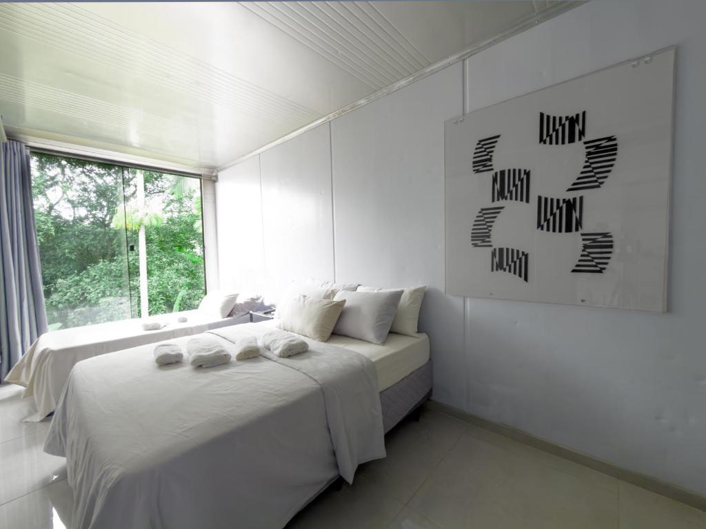 een witte slaapkamer met twee bedden en een raam bij Casa Container Moderna com Vista da Natureza em Itajaí in Itajaí