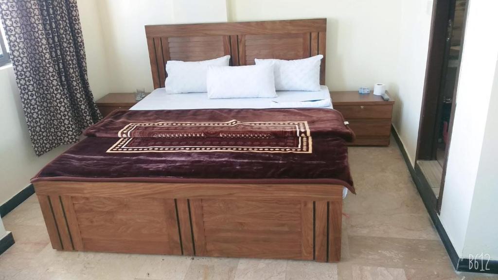 une chambre avec un grand lit avec une tête de lit en bois dans l'établissement All khair hotel, à Murree