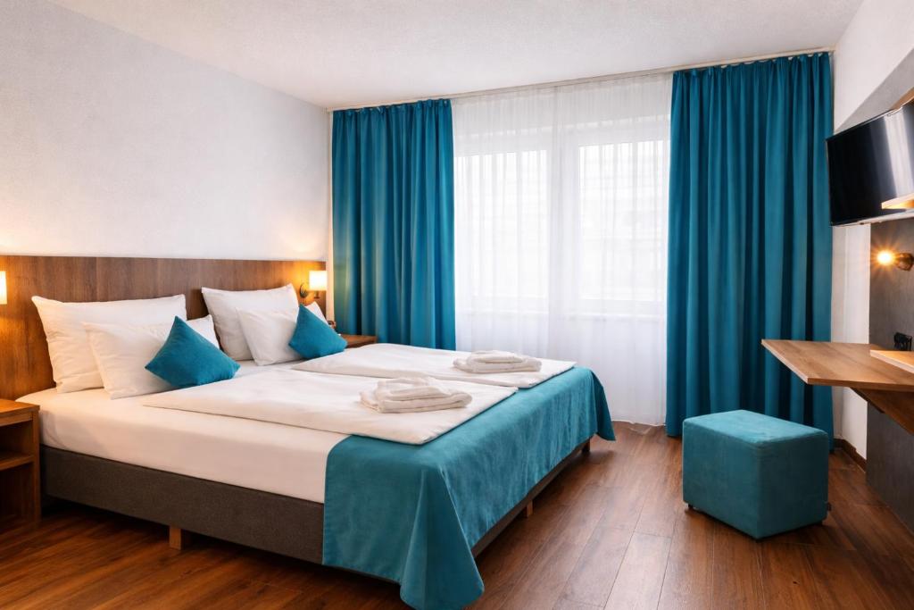 a bedroom with a large bed with blue curtains at Hotel Hansa Stuttgart City in Stuttgart