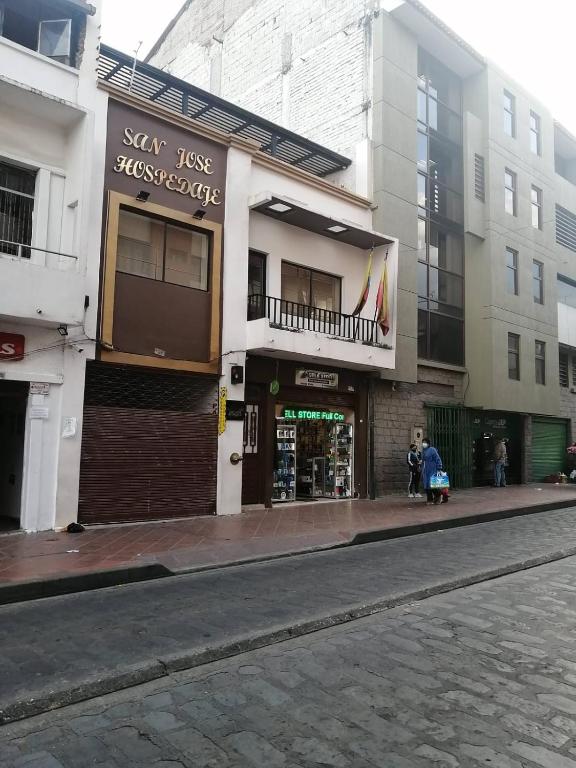 a building on a city street with people standing outside at San Jose hospedaje in Cuenca