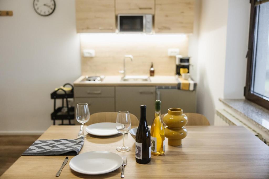 een houten tafel met twee borden en wijnglazen bij Apartma Castrum Vini in Ajdovščina