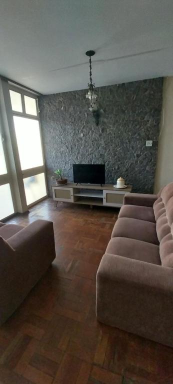 een woonkamer met een bank en een tv bij Descomplica Hostel in Assis