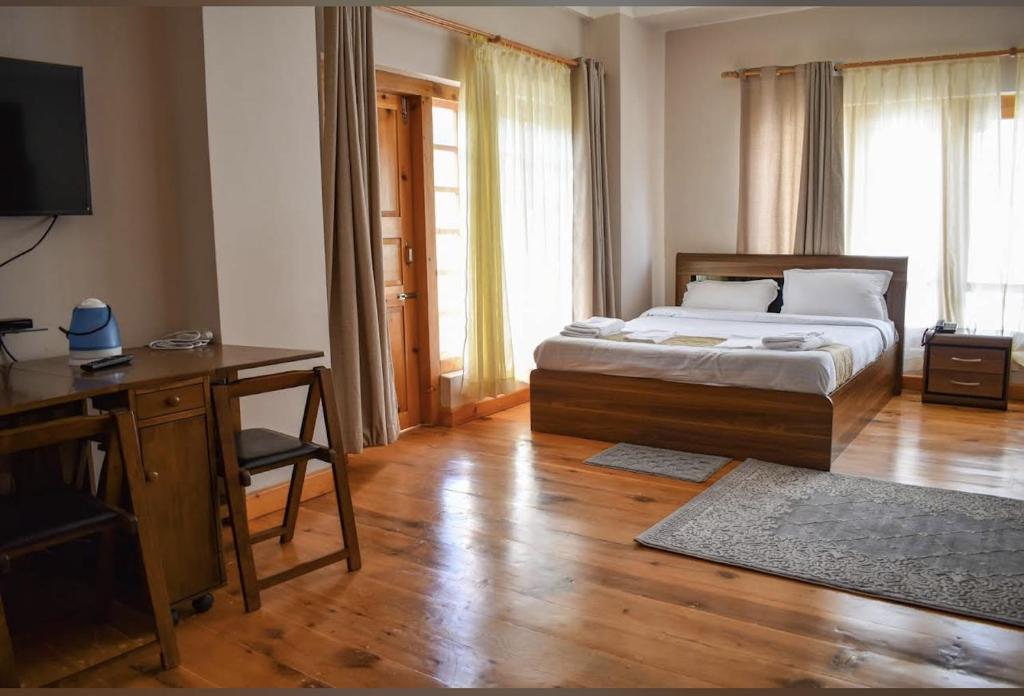 een slaapkamer met een bed, een bureau en een televisie bij GaiaYuel in Thimphu