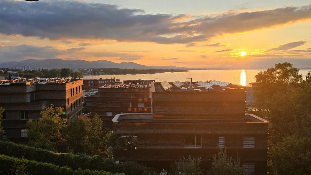 a sunset over a city with buildings and a body of water at Sunset View Apartment Bregenz Bodensee in Bregenz