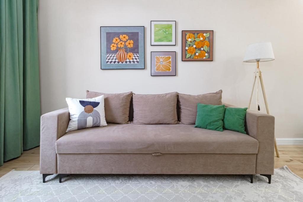a couch in a living room with paintings on the wall at Мандаринка in Taldykolʼ