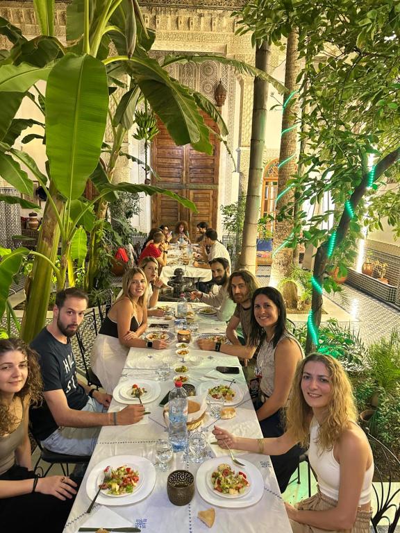 Un groupe de personnes assises à une longue table avec de la nourriture dans l'établissement RIAD LOUDAYA AND SPA, à Fès