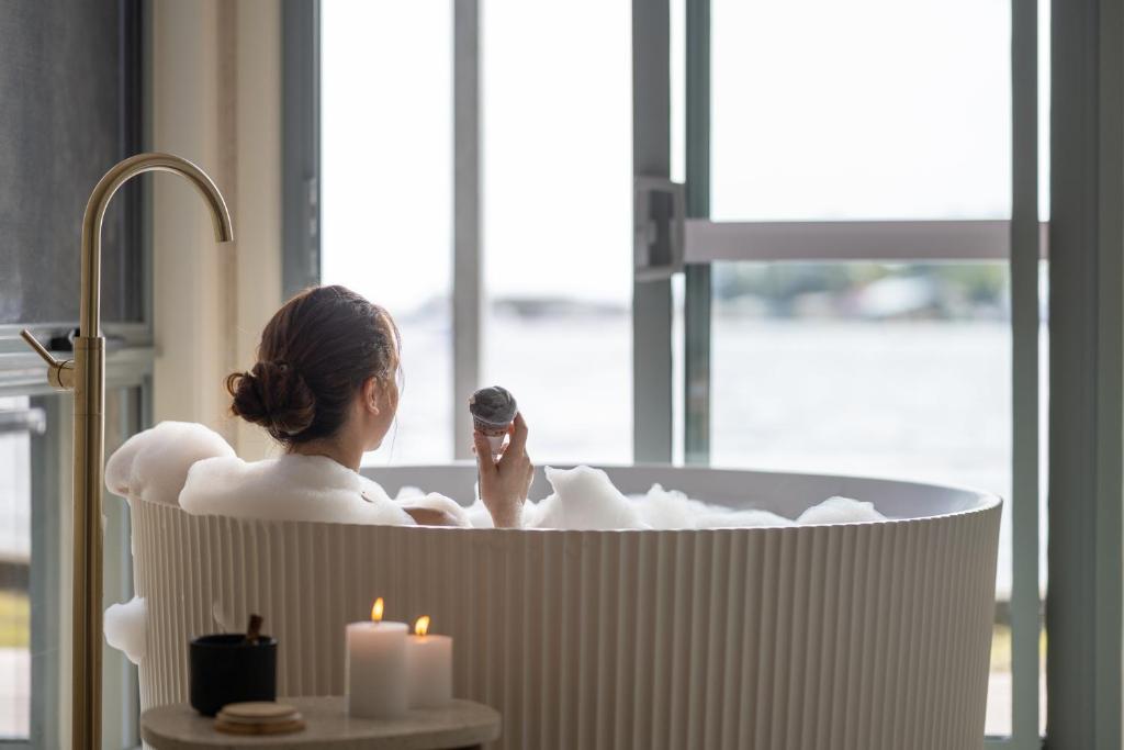 a woman in a bath tub with a microphone at Risby Cove Boutique Hotel in Strahan