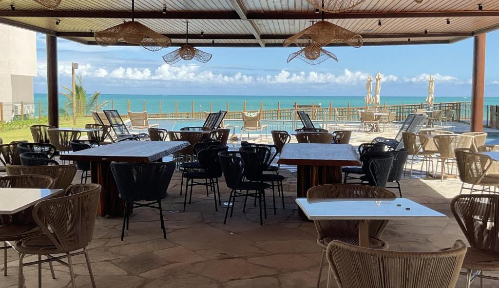 a patio with tables and chairs and a view of the ocean at Nomar Carneiros - Flat Beira-mar in Tamandaré