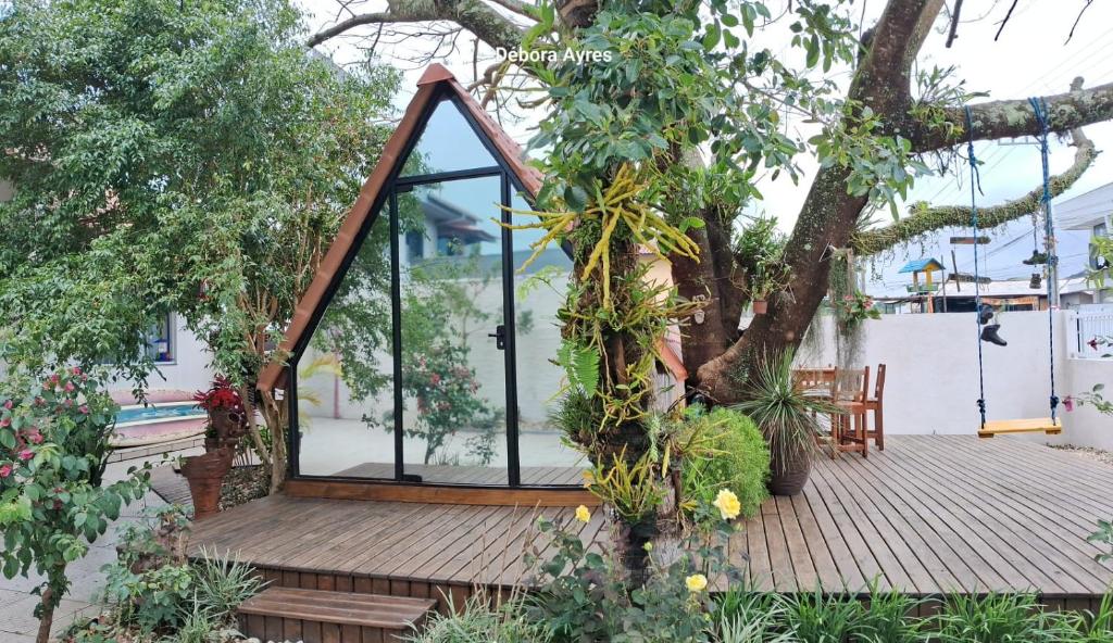 une maison en verre sur une terrasse en bois avec un arbre dans l'établissement Chalé Ecológico para 2 pessoas, à Bombinhas