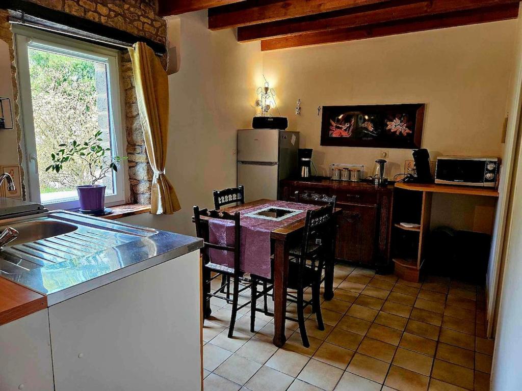 een keuken met een tafel, stoelen en een koelkast bij Gîte Cosy Cool in Languidic