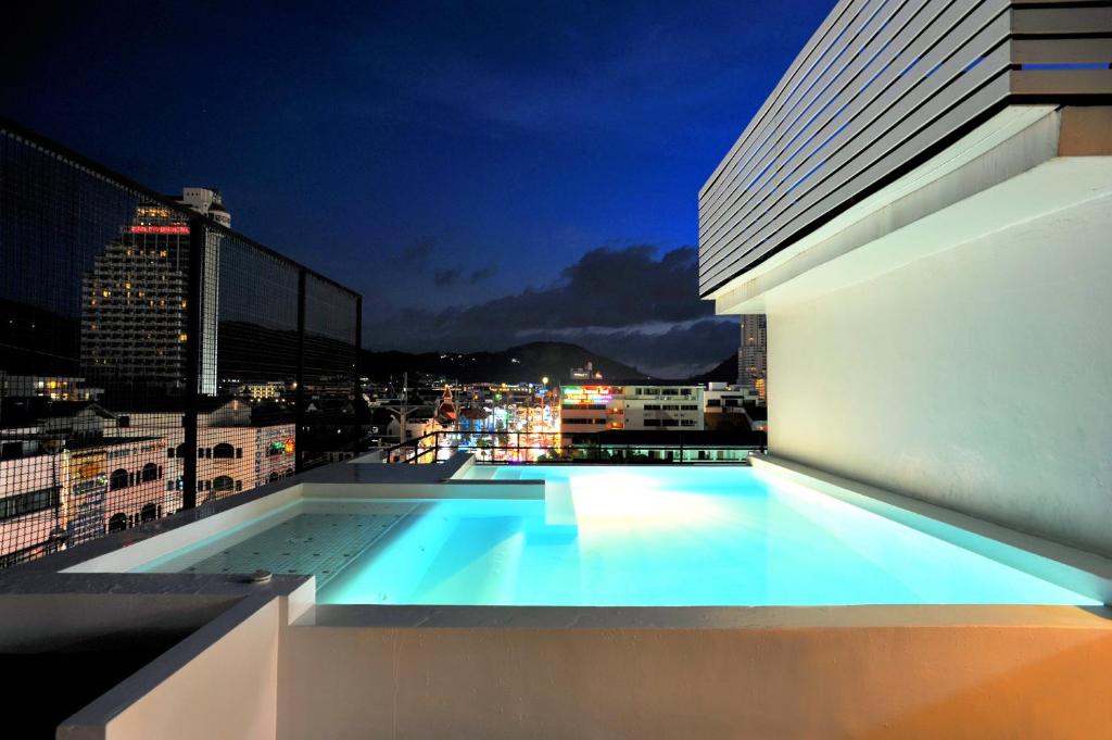 a swimming pool on the roof of a building at night at The Album Hotel in Patong Beach