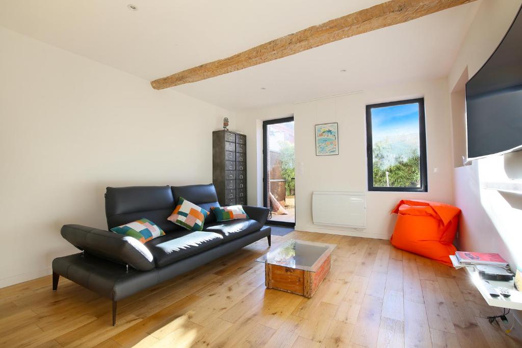 een woonkamer met een zwarte leren bank en een oranje stoel bij NEW - Maison brique 4p - Côte Pavée coeur Toulouse in Toulouse