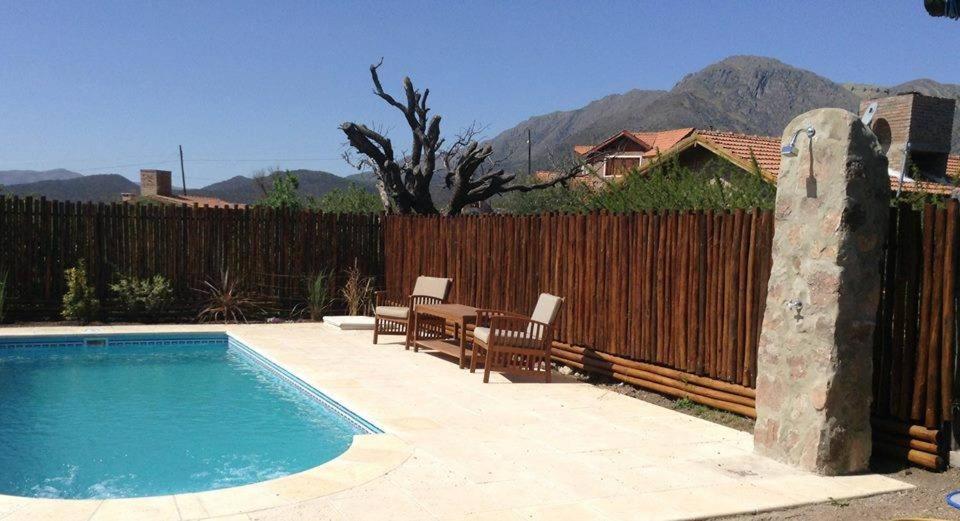 una piscina con mesa y sillas junto a una valla en Apart Cabaña La Unica en Capilla del Monte