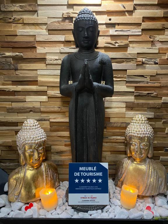 une statue de Bouddha en prière avec des bougies devant un mur dans l'établissement Suite 5 étoiles 50 nuances plus zen avec Jacuzzi et jeu pour adulte, à Lagrâce-Dieu